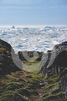 Arctic nature landscape with icebergs in Greenland icefjord with midnight sun sunset sunrise in the horizon. Early