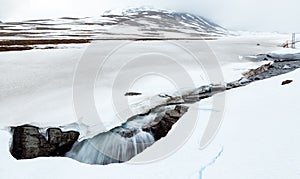 Arctic river falling into a hole in snow
