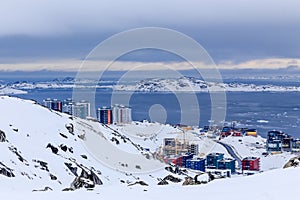 Arctic streets and building blocks of greenlandic capital Nuuk city at the fjord, view from snow hills, Greenland photo