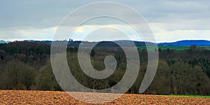 Ardennes landscape,with empty winter farmland and forests and hills on a rainy day with dark clouds