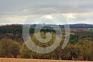 Ardennes landscape,with empty winter farmland and mixed forests and hills on a rainy day with dark clouds