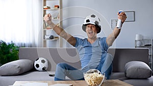 Ardent football supporter in fan hat rejoicing to scored penalty kick, victory