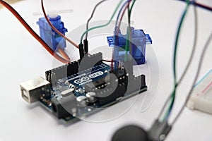 Arduino uno project with jumper wires connected to micro servo and joystick module isolated on white background