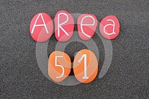 Area 51 sign composed with colored stones over black volcanic sand