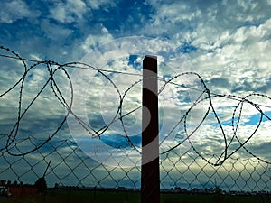 the area is fenced with barbed wire blue sky with clouds