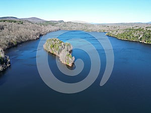 Areal view of a tranquil lake in New Hampshire, surrounded by lush green trees set in a wooded area