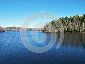 Areal view of a tranquil lake in New Hampshire, surrounded by lush green trees set in a wooded area