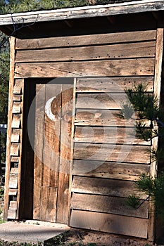 Vintage wooden outhouse with crescent moon on door