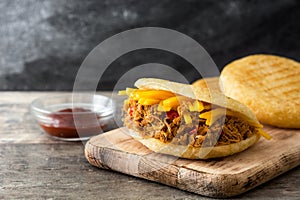 Arepa with shredded beef and cheese on wood. Venezuelan typical food