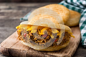 Arepa with shredded beef and cheese on wooden background. Venezuelan typical food photo