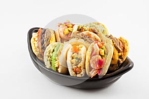 Arepas with assorted fillings served in a black ceramic dish