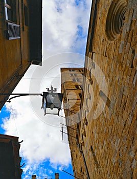 AREZZO, ITALY  Cityscape with lamp against cloudy blue sky in Arezzo with facade of old historical buildings and church , Tuscany,