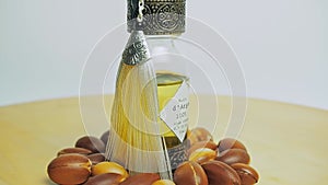 Argan oil in a oriental glass and metal bottle motion on wooden table and white background.