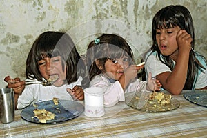 Poor hungry Argentinian girls eat in a soup kitchen