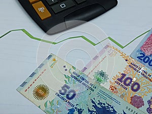 argentine banknotes and calculator on background with rising trend green line