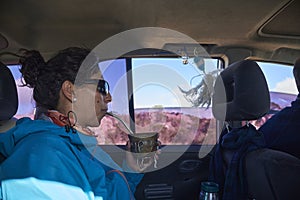 Argentine woman riding in the back of a car, enjoying drinking mate