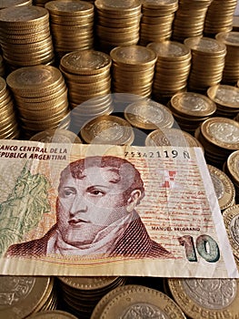 argentinean banknote of ten pesos and stacked coins of ten mexican pesos