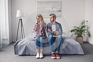 argued young couple sitting on bed at home, relationship photo