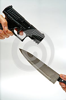 arguing gun vs knife - woman hand holding black gun and man holding big kitchen knife