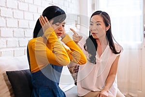 Argument between annoyed Asian teenage daughter and upset middle aged mother. photo