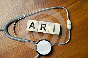 ari inscription on wooden cubes isolated on white background, medicine concept. Nearby on the table are a stethoscope and pills