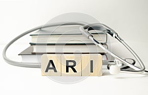 ari inscription on wooden cubes isolated on white background, medicine concept. Nearby on the table are a stethoscope and pills