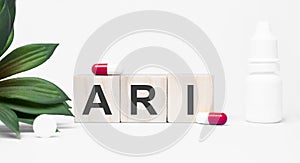 ARI the word is written on wooden cubes,plant and red pills,on white background