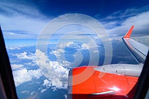 Clouds in the sky and cityscapes though airplane window. Red aeroplane flying photo