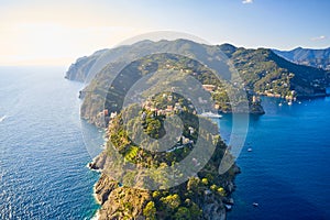 Arial view on the mountain range with a white lighthouse near Ligurian sea on the foreground. Tradition colorful italian houses