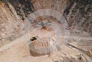 Arial view of the open pit mine. Front end loader loading gravel into stone jaw crusher in open-pit. Limestone quarry development