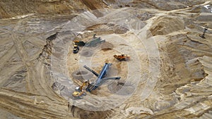 Arial view of the open pit mine. Front end loader loading sand into stone jaw crusher in open-pit. Heavy machinery