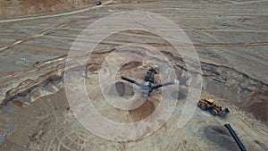 Arial view of the open pit mine. Front end loader loading sand into stone jaw crusher in open-pit. Heavy machinery working in