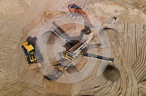 Arial view of the sand open-pit mining with heavy mining machinery. Mobile stone jaw crusher machine in open pit mine. Wheel