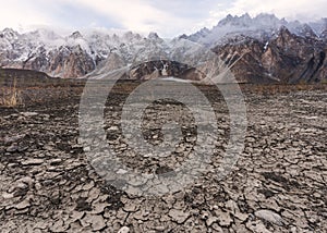 Arid climate, dry cracked drought field with Passu Cathedral mountain landscape in Pakistan photo