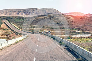 An arid hot desert with mountains and a road under a blue sky