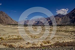 Arid lands of ladakh with barren himalayan peaks viewable in distance with deep blue sky