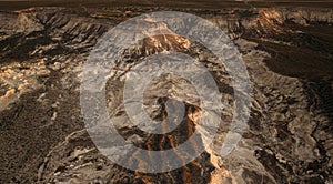 Arid remote badlands with erosional features in the semi-desert during golden hour. Aerial view