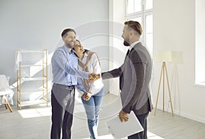 Ariendly realtor shakes hands with young married couple who have just purchased this house.