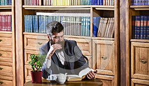 Aristocrat on thoughtful face reading book. Oldfashioned man near cup
