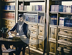 Aristocratic lifestyle concept. Man in classic suit sits in vintage interior, library