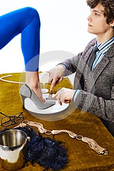 Aristocratic man, young guy in office suit eating female leg in blue leggings like delicious dish in restaurant.