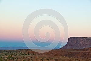 De color naranja y azul, puesta de sol sobre el desierto de Arizona, en el Valle del Monumento en Americanos Nativos Navajo de la tierra, con una mesa visible y espacio para texto.