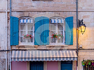 Arles. Window in the orange facade of the old house decorated with flowers.