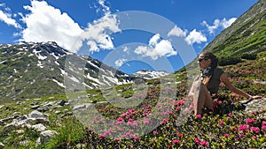 Arlhoehe - A woman sitting between Alpine roses and enjoying the summer day in the mountains