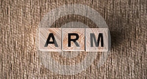 ARM Advanced RISC Machines word written on wooden blocks on a brown background