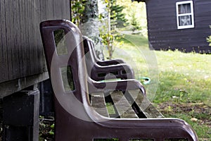 Arm of a bench set against the shade of a wall of a lake cabin