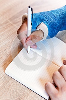 Arm with blue cast and notepad