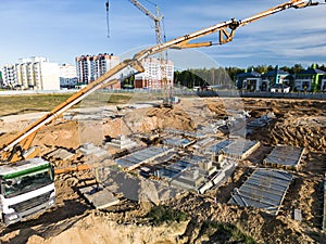 Arm of concrete pump ready for concrete conveying at construction site. Jib of concrete pump truck against sky at background.