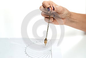 Arm of dowser with hand-held pendulum over the chart.