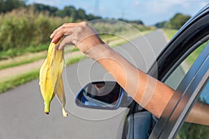 Arm dropping peel of banana out car window